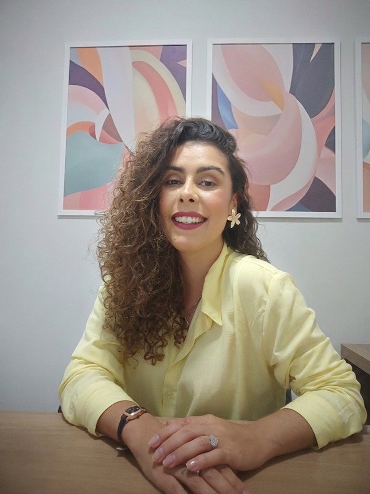 Ana Carolina Gomes Souza, psicóloga, sentada à mesa do consultório.